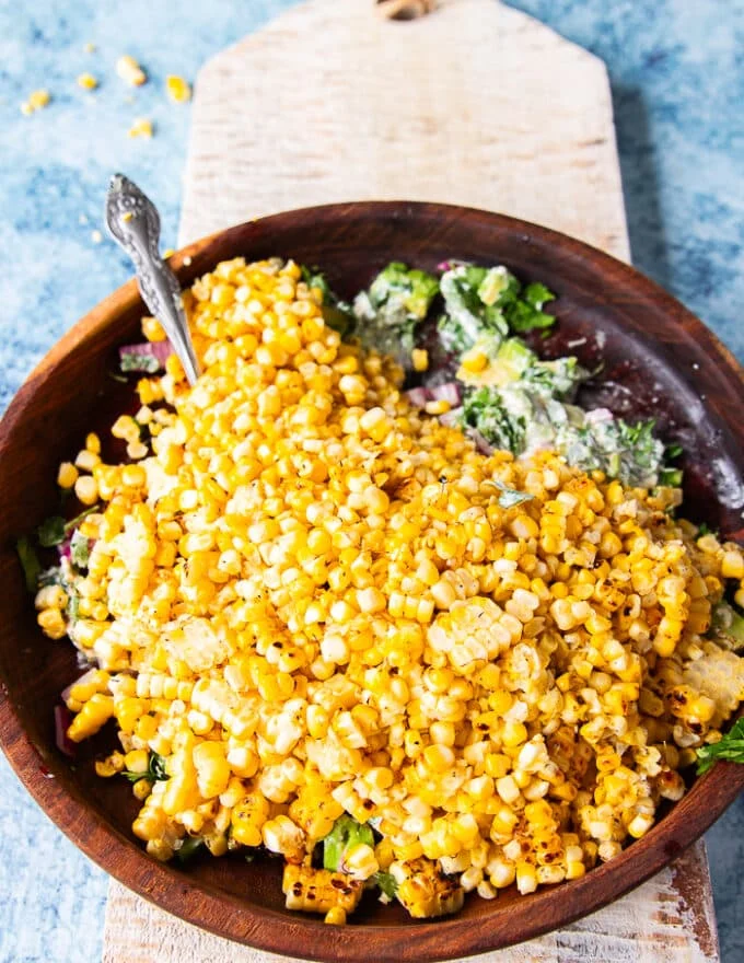 The corn kernels are added to the salad bowl along with avocados and cotija cheese