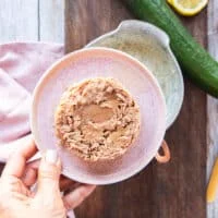drained canned tuna in a plate and a hand holding it