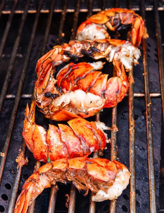 Lobster tails cooked perfectly on the grill, curled up and pink