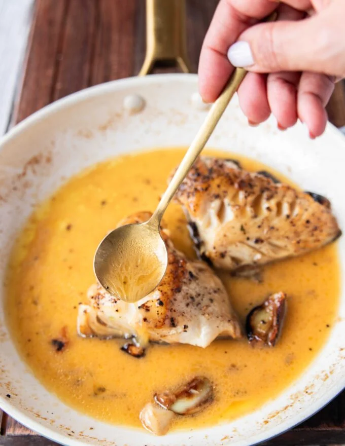 basting the fish with hot butter sauce to absorb it fully