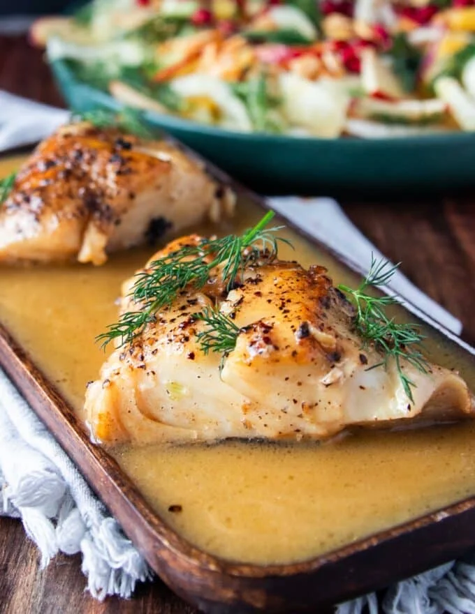 close up of black cod fish drenched in lemon garlic butter sauce