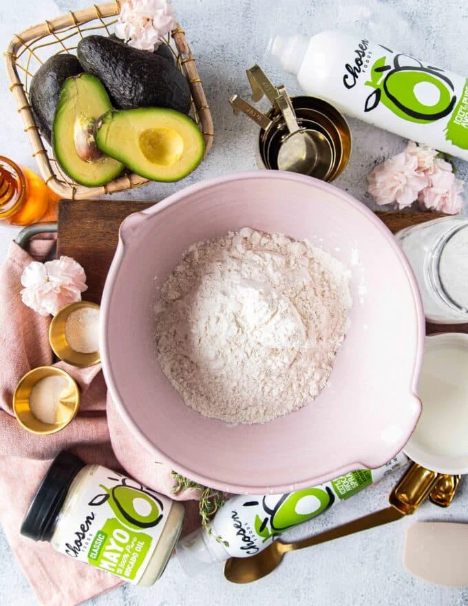 Ingredients to make the mayonnaise biscuits on a bowd including flour, baking powder, sugar, salt, milk and mayonnaise