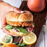 A hand holding salmon burgers assembled and ready