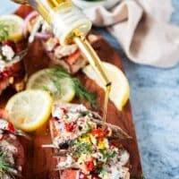 A bottle drizzling some olive oil over the sardines on toast to finish the recipe