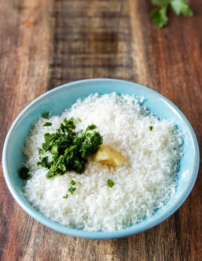 A bowl with parmesan , garlic and parsley