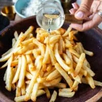 Pouring truffle oil for truffle flavor over the cooked potatoes fries