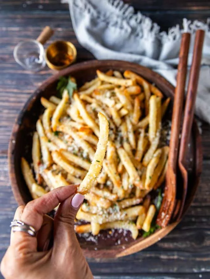 A hand holding. truffle fries