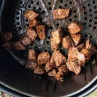 Golden brown and juicy air fryer steak bites in the air fryer basket