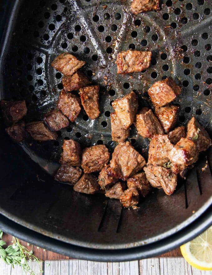Golden brown and juicy air fryer steak bites in the air fryer basket