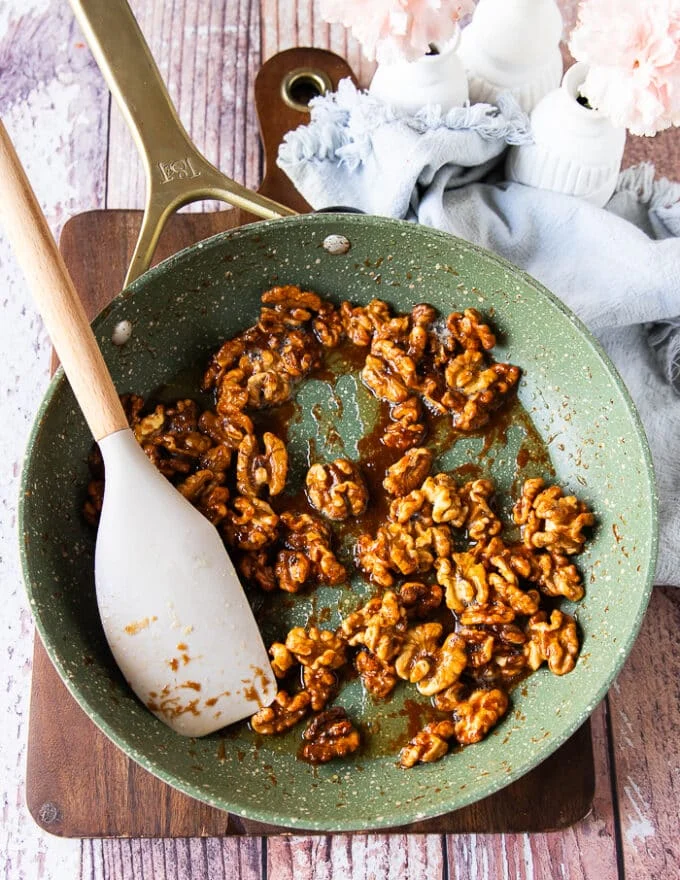 Golden walnuts with a glossy shine in the skillet now ready to cool