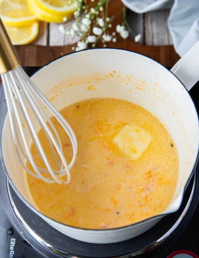 Whisking the butter into the beurre blanc one a time to make beurre blanc sauce