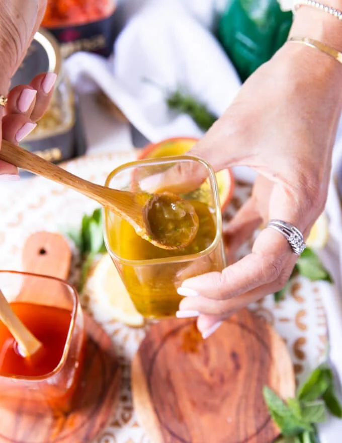 A hand holding a green harissa vinaigrette