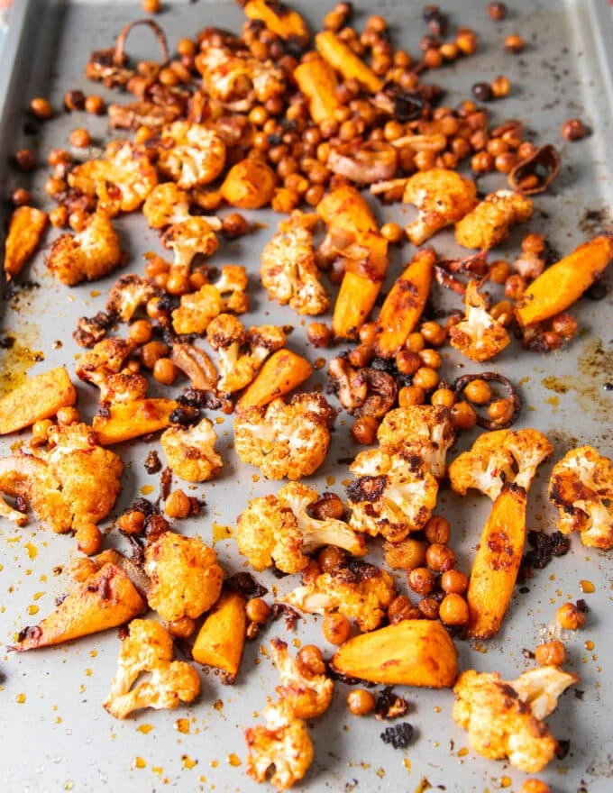 tender and sweet caramelized roast cauliflower and crunchy chickpeas roasted in a baking sheet ready to make cauliflower salad.