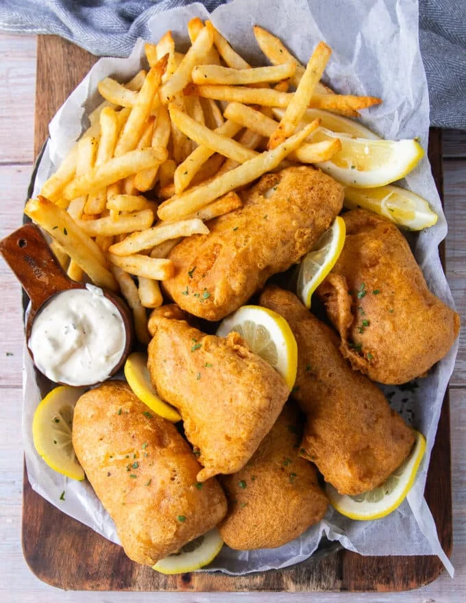 A full plate of fish and chips with lemon wedges and tartare sauce