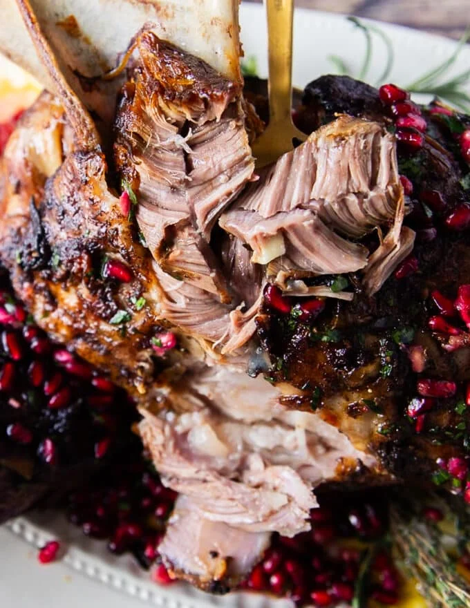 close up of lamb meat flaking apart using a fork showing how tender the lamb shoulder is