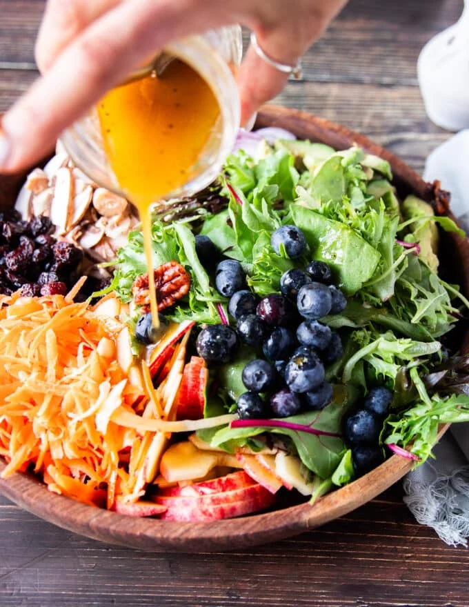 maple vinaigrette being poured over the salad
