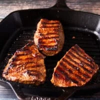 flank steak is cooked in a super hot skillet or outdoor grill showing grill marks