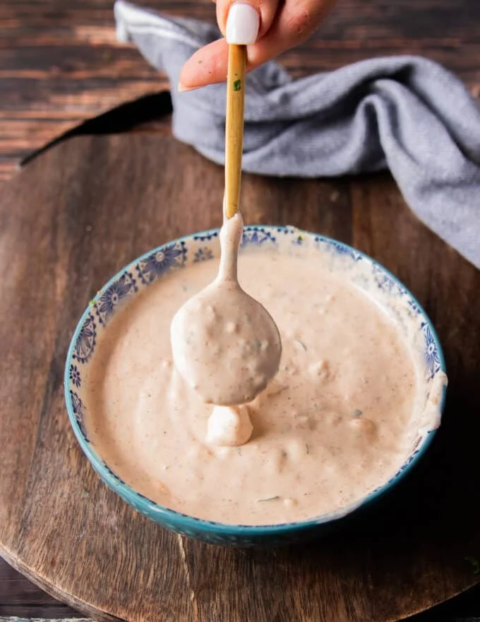 dripping taco sauce from a spoon onto a plate showing the texture