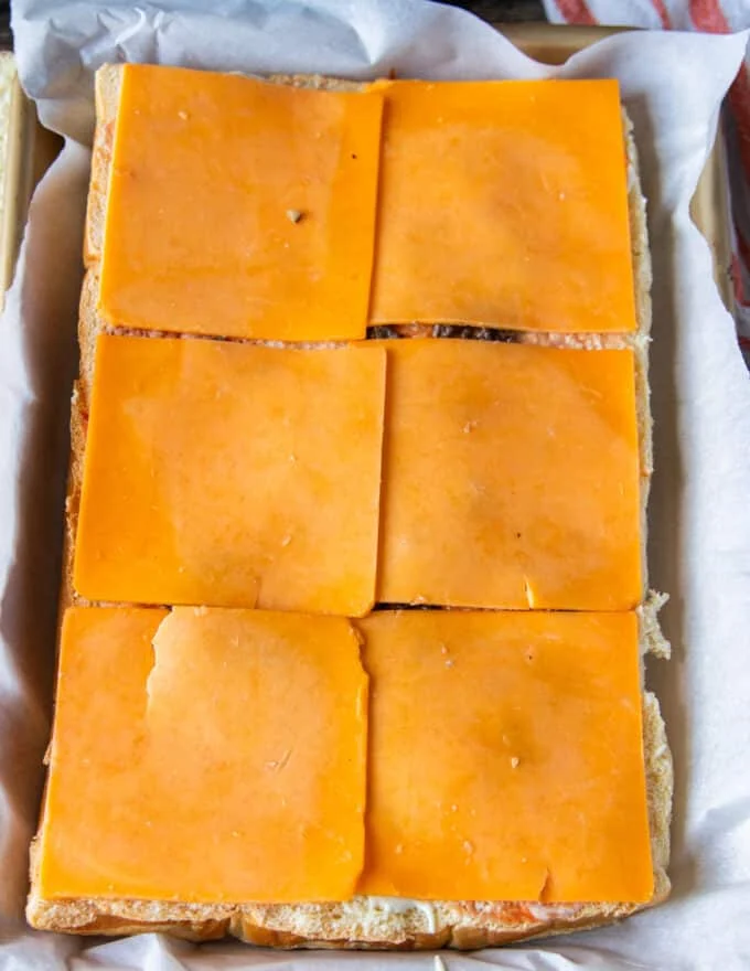 A layer of sauce and cheese are added at the bottom of the slider bread