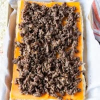 burger meat is added over the cheese