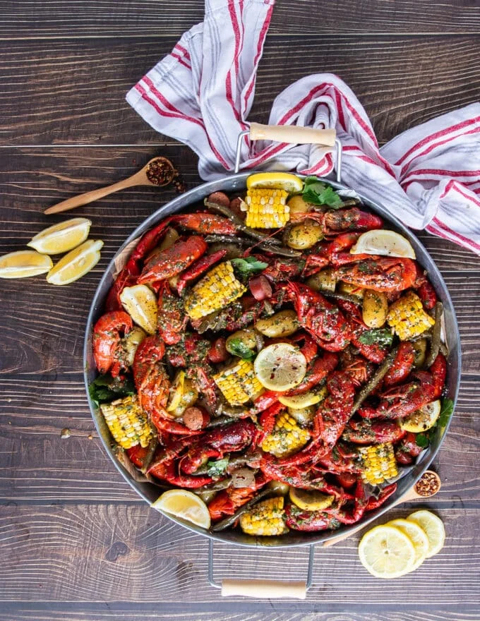 top view of a spread of crawfish boil with crawfish, corn, potatoes, sausage and lemon