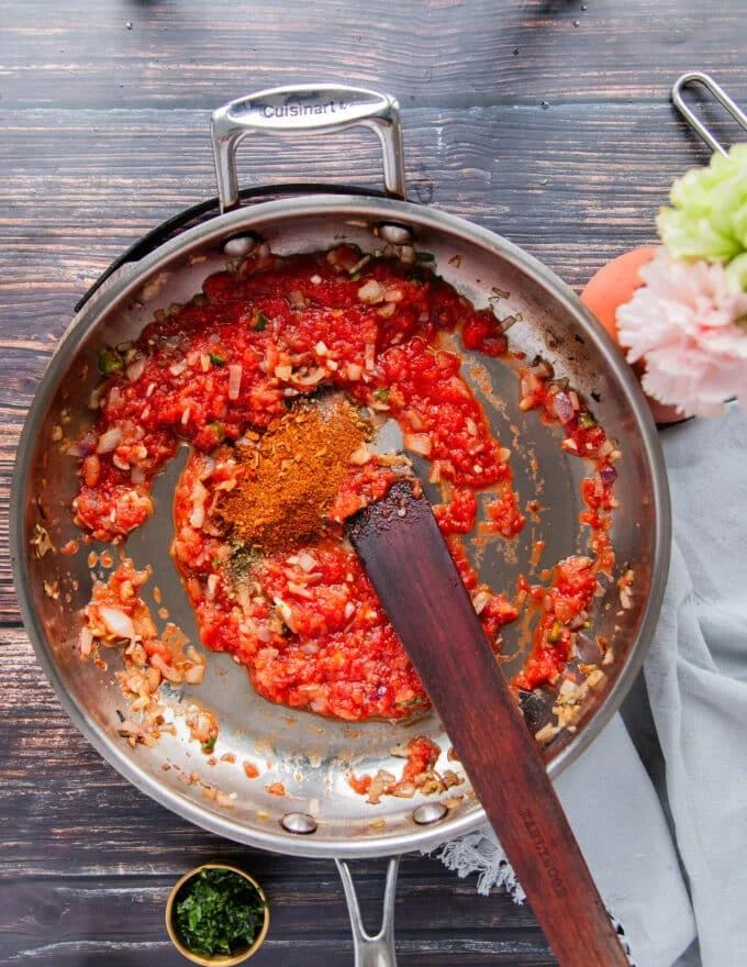 Tomatoes and seasoning are added to the sauce pan