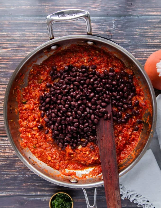 Black beans are added to the pan to continue cooking
