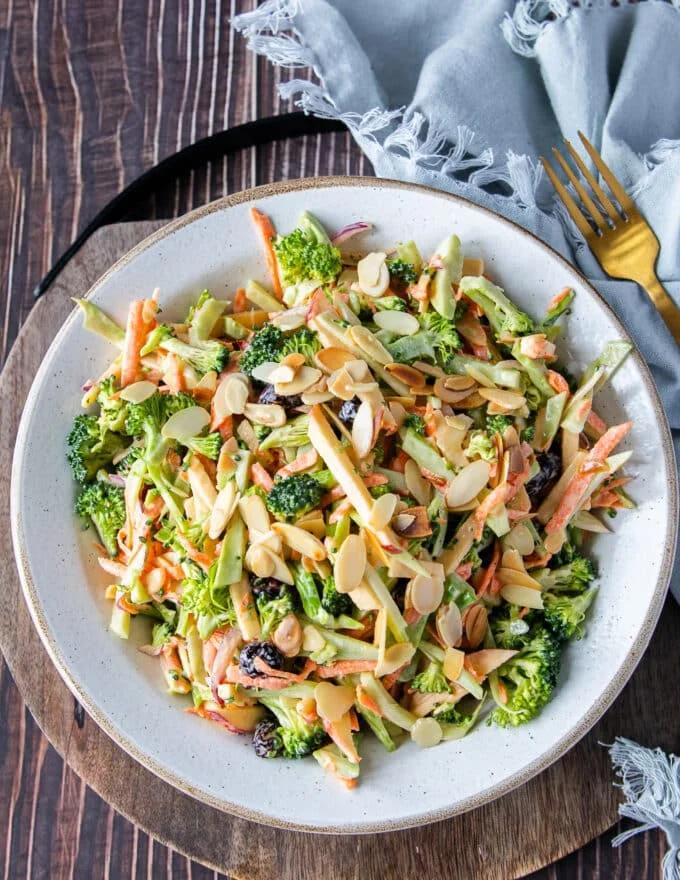 A perfect bowl of broccoli slaw with toasted nuts on top and perfectly dressed