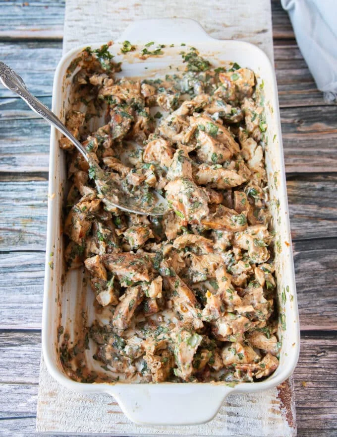 shredded chicken mixed with the flavoring herbs and sauce in a shallow plate