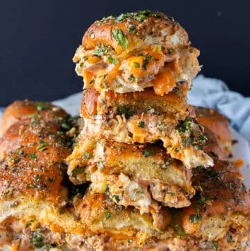 close up of a tower of 4 stacked chicken sliders with cheese oozing out and soft bread
