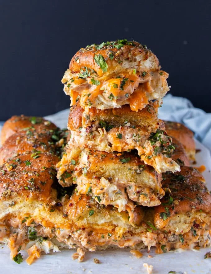 close up of a tower of 4 stacked chicken sliders with cheese oozing out and soft bread