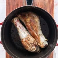 flipped and golden brown lamb shanks in the dutch oven