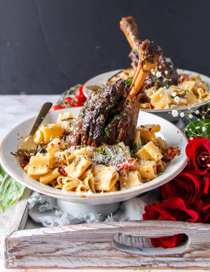 close up of one slow cooked lamb shanks showing fall off the bone soft lamb