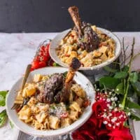 tender and fall off the bone lamb shanks with some tomatoes on the side and sun dried tomato pats and parmesan to garnish