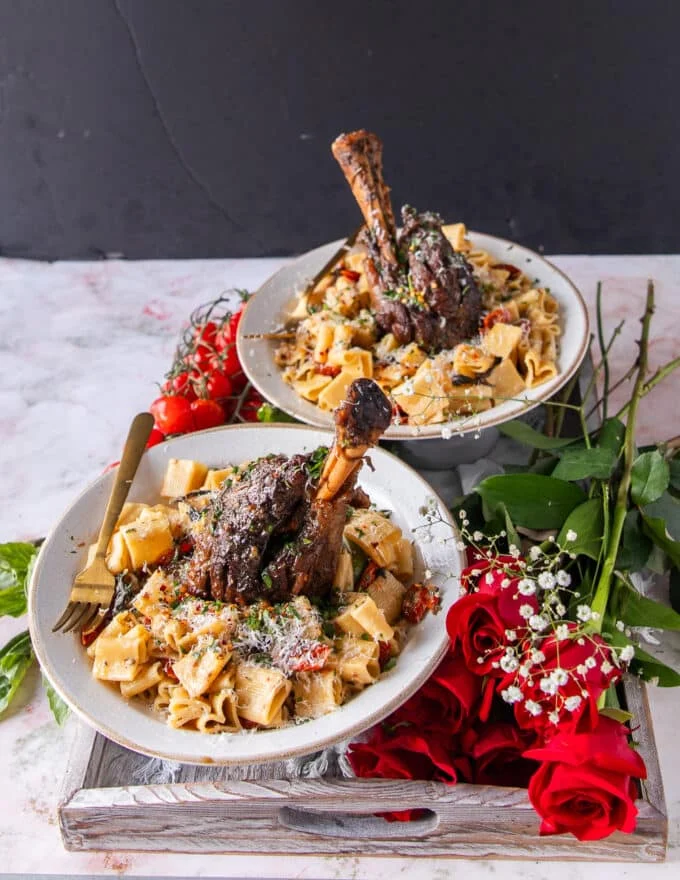 tender and fall off the bone lamb shanks with some tomatoes on the side and sun dried tomato pats and parmesan to garnish