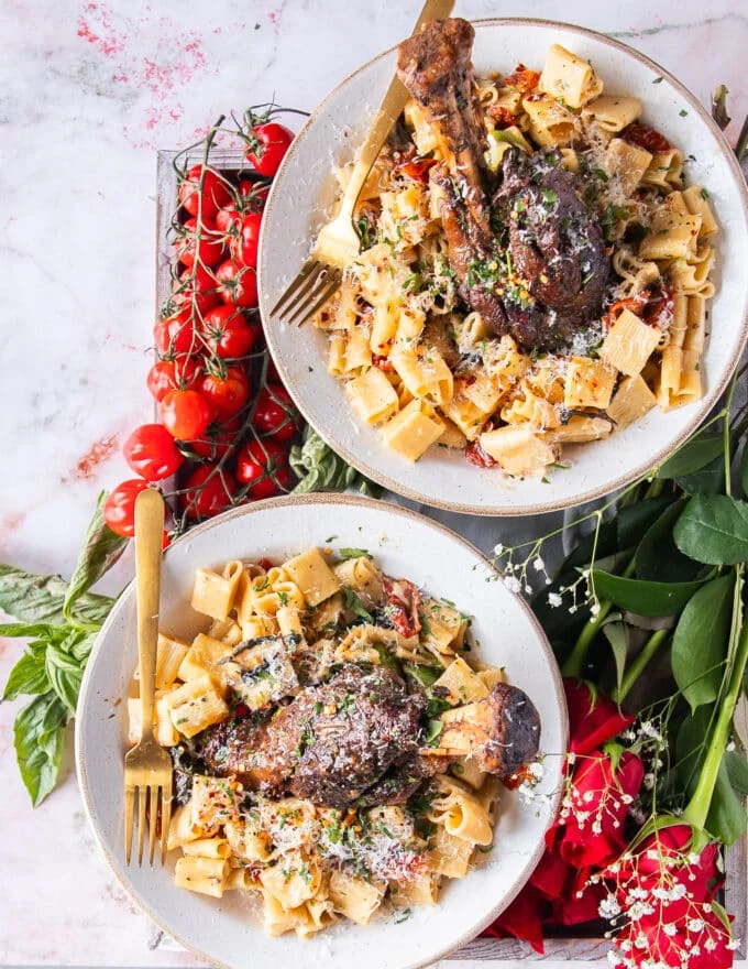 top view of two plates of pasta and lamb shanks slow cooked until perfect