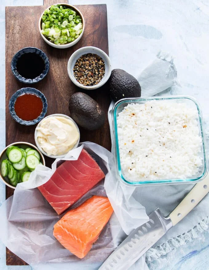 All ingredients required to make the best sushi cake on a wooden board, each in a small bowl