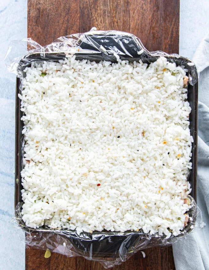 A final layer of the remaining rice is added on top and pressed down