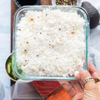 a hand holding ready cooked ans seasoned sushi rice in a bowl ready to use