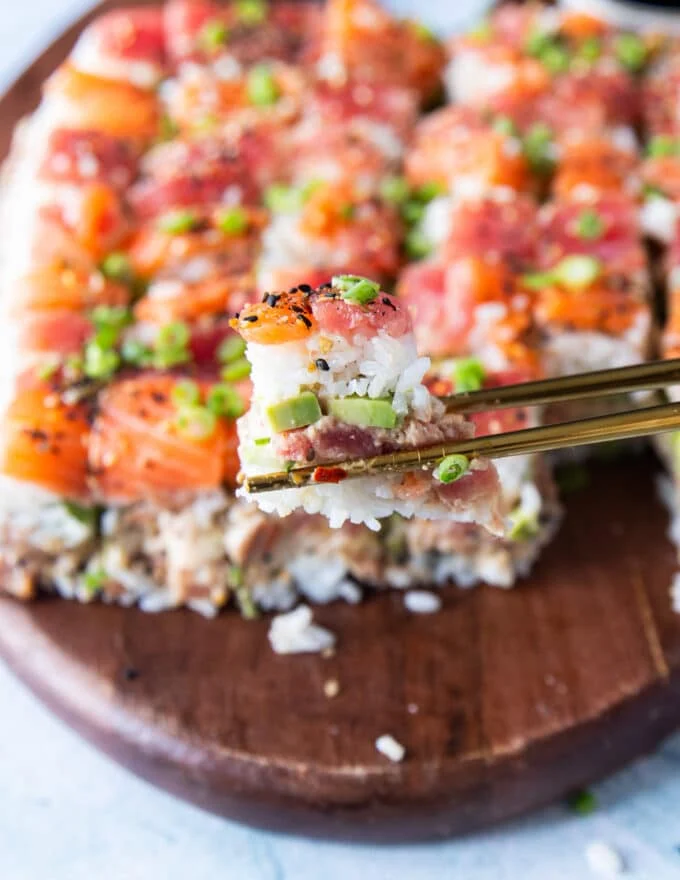 A chop stick holding a pice of the sushi cake close up showing the layers