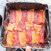 A ray os thinly sliced ahi tuna and sushi grade salmon are arranged a the bottom of the dish to make the fist layer of the cake when flipped.
