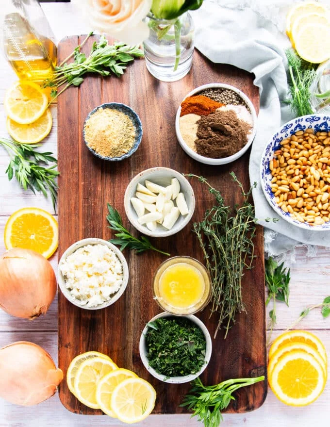 Ingredients to make the marinade and cook a butterflied leg of lamb in small bowls on a cooking board