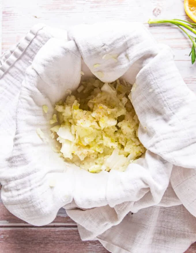 onions grated in a towel showing how to squeeze it