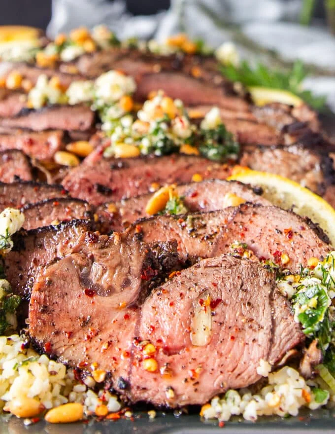 close up butterflied leg of lamb seasoned with black pepper and olive oil
