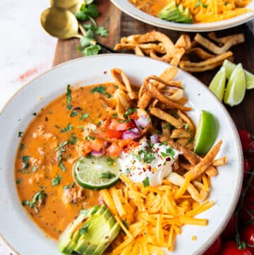 one bowl of perfect chicken taco soup close up topped with tortillas, avocado, sour cream, cilantro and cheese