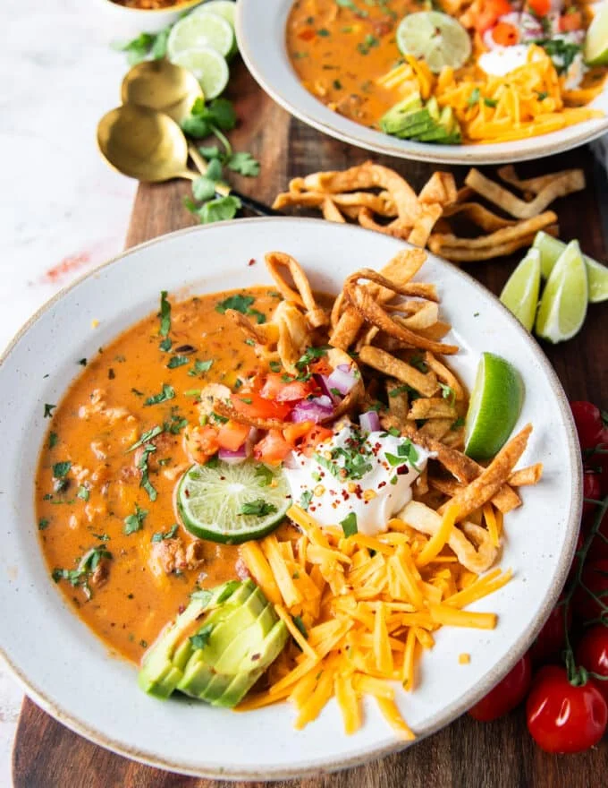 one bowl of perfect chicken taco soup close up topped with tortillas, avocado, sour cream, cilantro and cheese