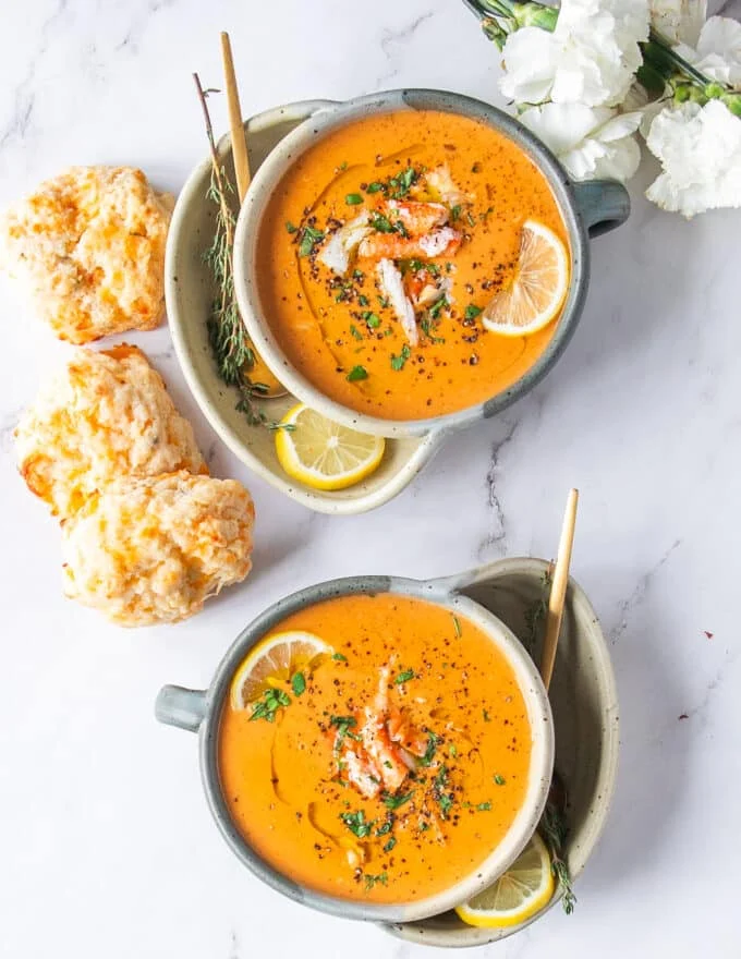 two bowls of crab bisque creamy and delicious garnished with lemon slices and fresh parsley served with drop biscuits