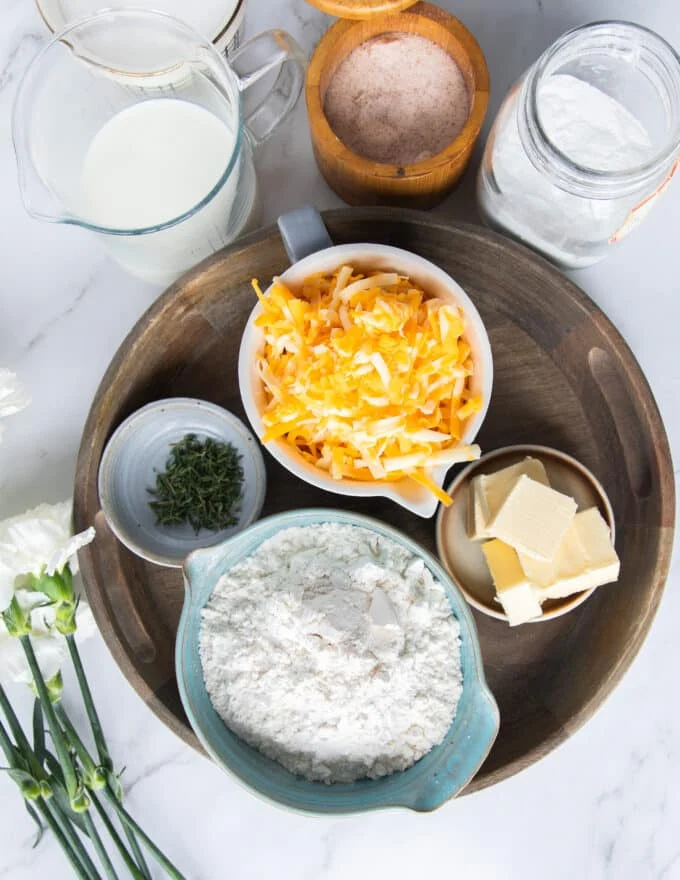 Ingredients to make drop biscuits recipe in small bowls on a large tray