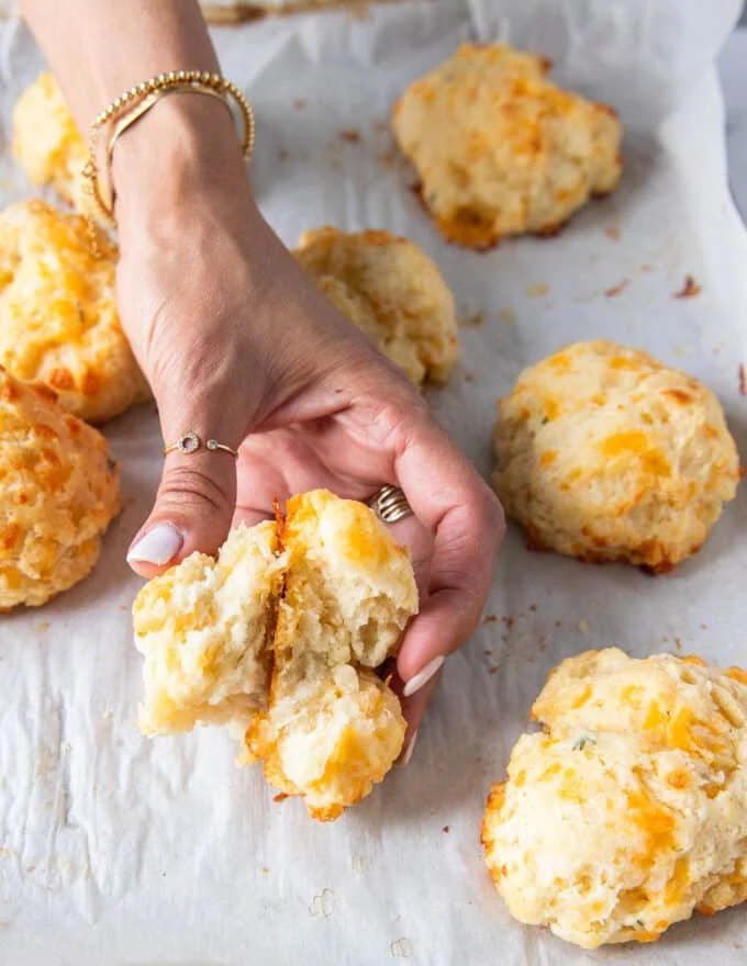 A hand holding a broken up drop biscuit showing the perfect texture inside