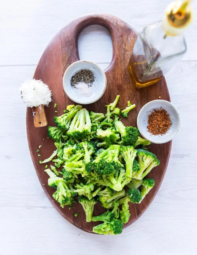 ingredients to make frozen broccoli in air fryer on a board gathered in small bowls